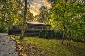 A modern building with a sloped roof, surrounded by a wooden fence and several coniferous trees.