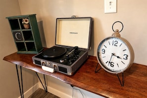 A vintage record player in a case with a clock beside it on a wooden table.