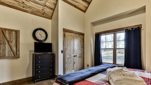 A bedroom with a bed, a dresser, a clock, and a window with curtains.