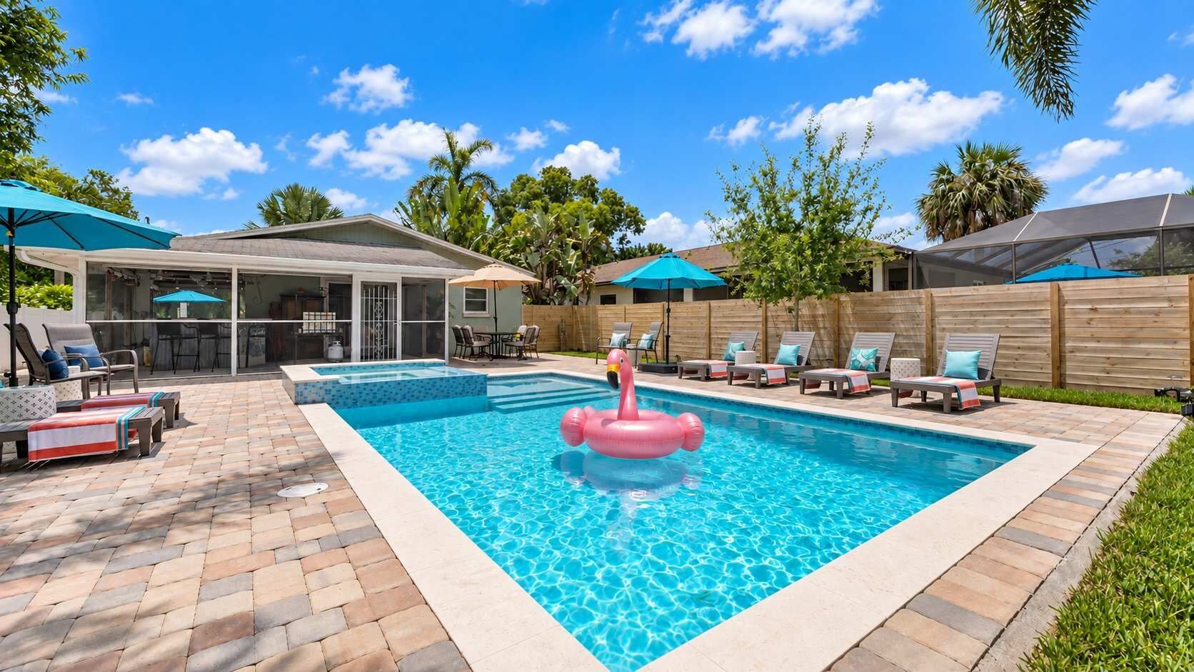A backyard with a swimming pool, lounge chairs, and a covered patio area.