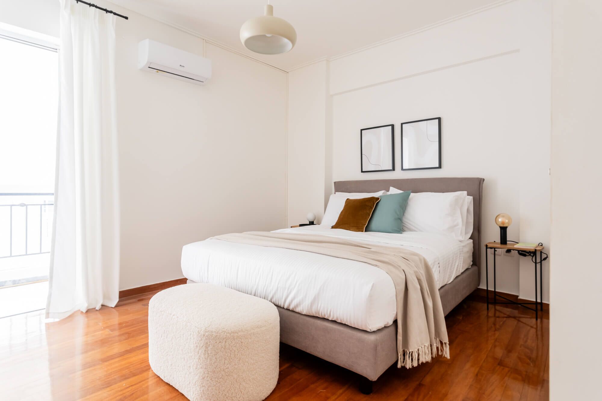 A modern bedroom with a bed, bedside table, and a hanging light fixture.