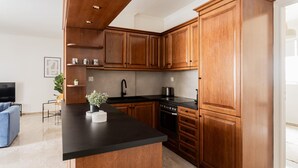 A modern kitchen with wooden cabinets, a black countertop, and a built-in oven. - Faliro Sunlit 3BR Apartment (Palaio Faliro)