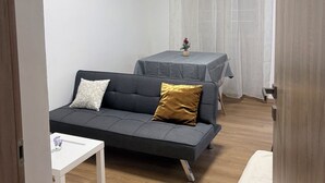 A modern living room with a grey sofa, a small white table, and a dining table with a grey tablecloth. - ApartUry at TorinoMetroStop (Torino)