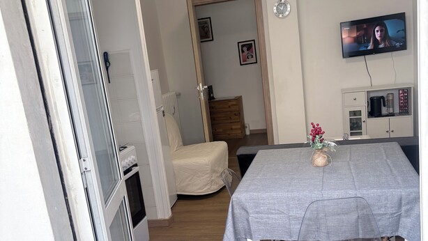 A room with a dining table, a TV, and a chair. - ApartUry at TorinoMetroStop (Torino)