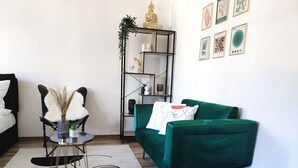 Una sala de estar moderna con un sofá verde, una mesita auxiliar con un florero y una alfombra blanco y negro.