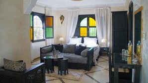 A room with a sofa, a small table, a bed with curtains, and a mirror. - Villa Atika Maison d'hôtes & SPA (Marrakech)
