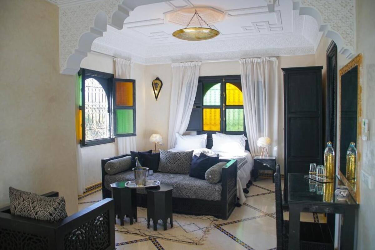 A room with a sofa, a small table, a bed with curtains, and a mirror.