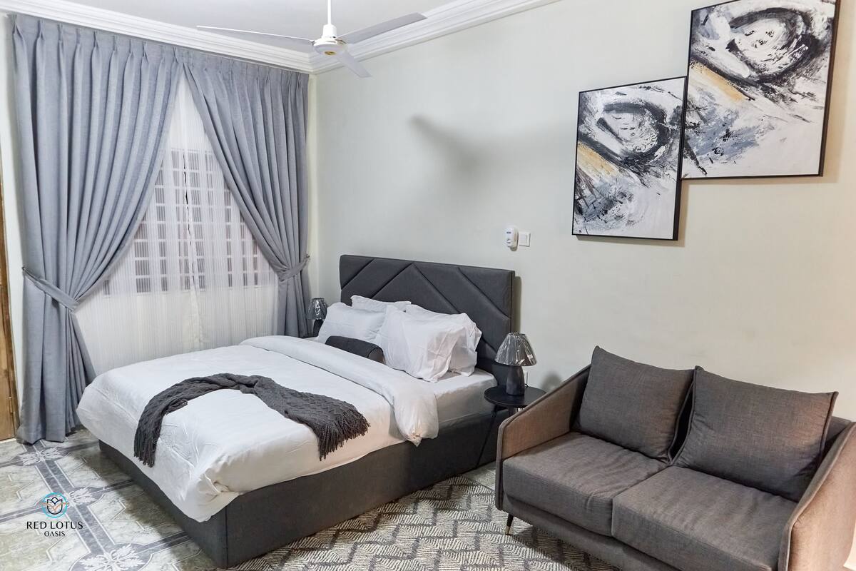 Une chambre à coucher avec un lit, un canapé et des œuvres d’art abstrait accrochées au mur.