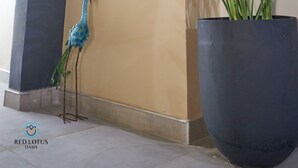 A lobby with a large potted plant, a wooden sculpture, and a peacock statue. - Red Lotus Oasis (Accra)