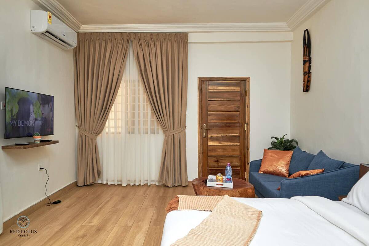 Une chambre d’hôtel avec un lit, une télévision, une porte en bois et une fenêtre avec des rideaux.