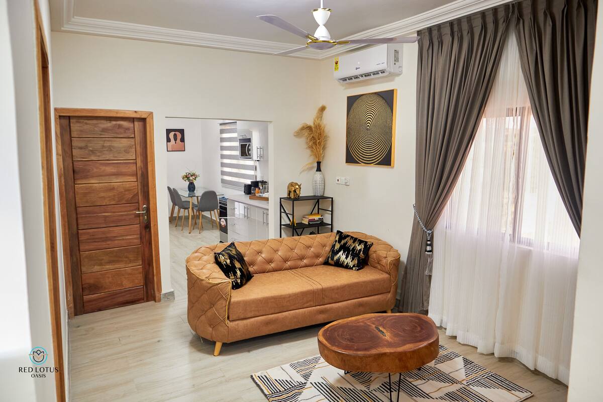 Un salon avec un canapé marron, une table basse ronde en bois et un tapis à motifs.