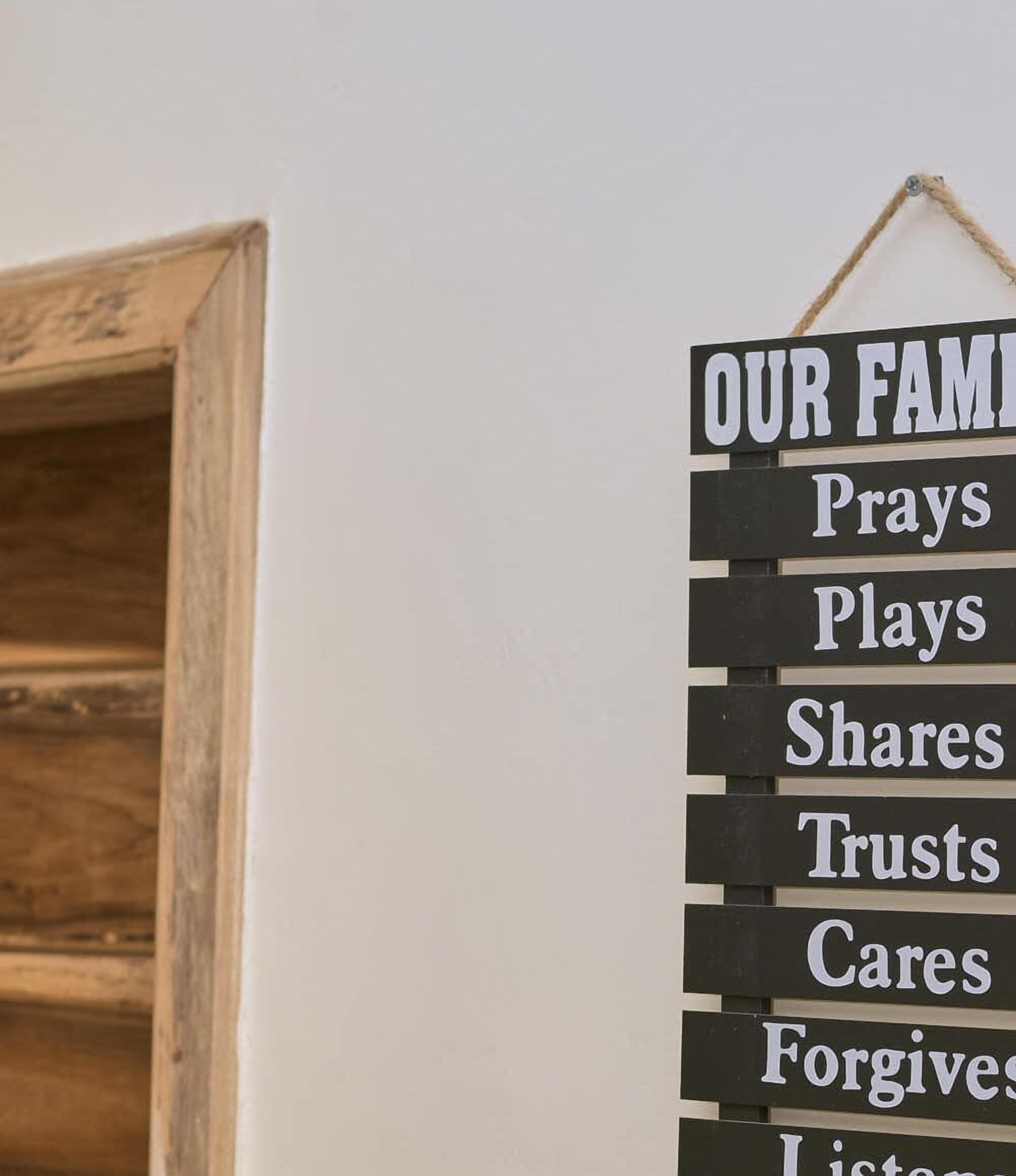 A sign with the words "OUR FAMILY Prays Plays Shares Trusts Cares Forgives Listens" on a wall.