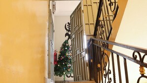 A staircase with a metal railing and a Christmas tree decorated with ornaments. - Red Lotus Oasis (Accra)