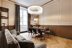 Un espace repas agrémenté d’un lustre, de boiseries et offrant une vue par une fenêtre.