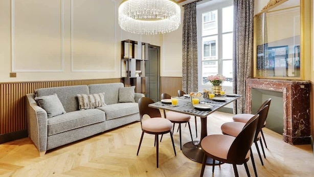 A modern dining area with a chandelier, a sofa, and a fireplace.