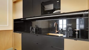 A modern kitchen with black cabinetry, a stainless steel sink, and a microwave above the counter.