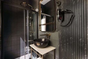 Une salle de bain moderne avec une douche à parois de verre, un lavabo sur colonne et un grand miroir.