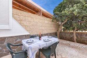 An outdoor dining area with a table set for four, surrounded by stone walls and a tree. - 3698 La Spiaggetta - Bilo Beach by Barbarhouse (Porto Cesareo)