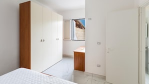 Un dormitorio con cama, armario y escritorio.