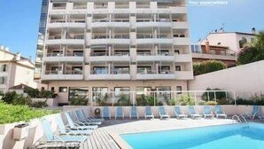 Un edificio moderno de varios pisos con un área de piscina en la azotea.