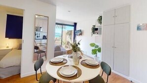 Un comedor con una mesa redonda para cuatro, una cocina al fondo y un armario grande.