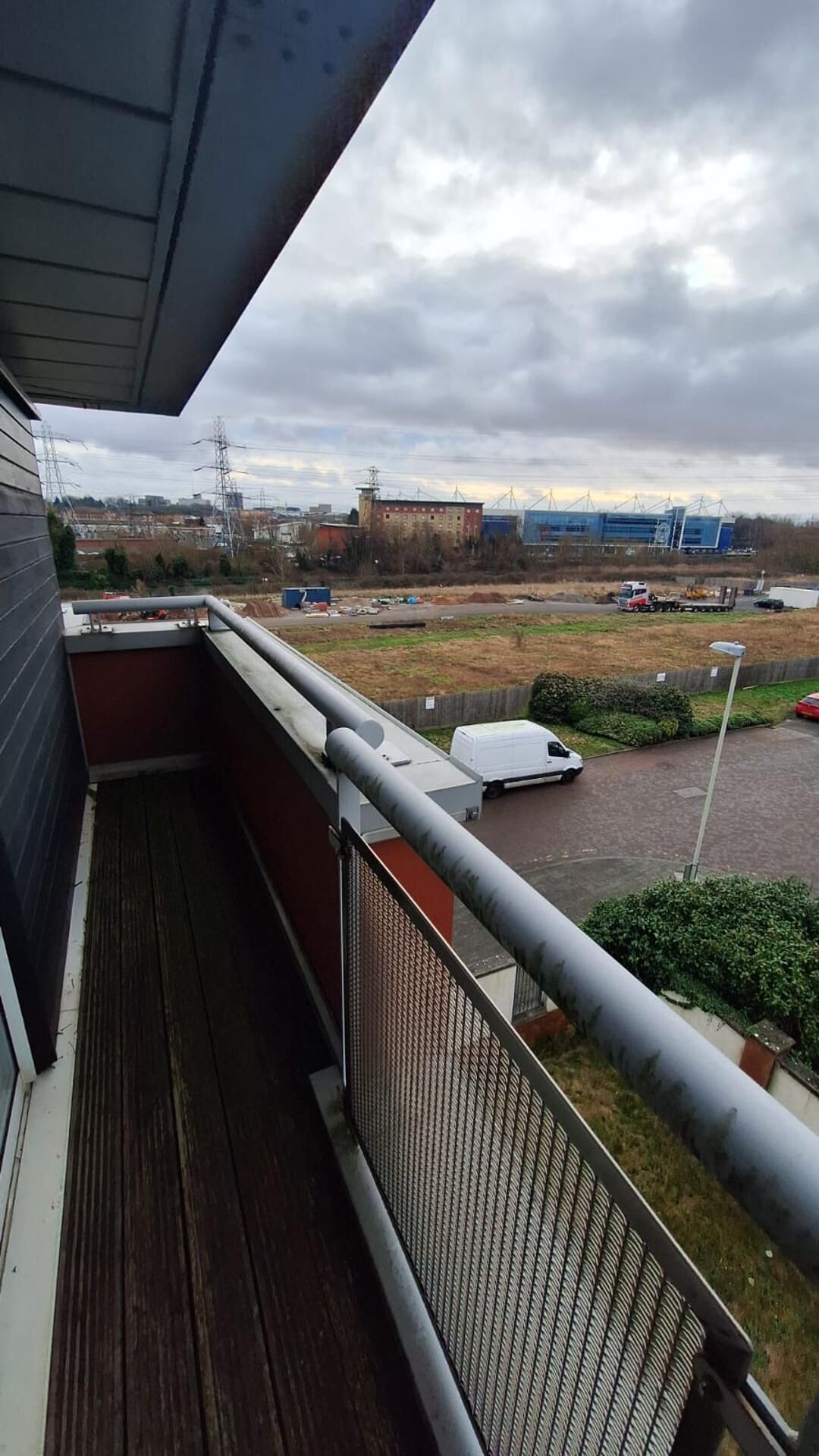 A balcony with a view of a parking area and industrial buildings.