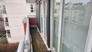 Un balcone con pavimento in legno, ampie porte scorrevoli in vetro e ringhiera in metallo.