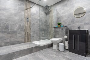 A modern bathroom with a bathtub, toilet, and a black cabinet.