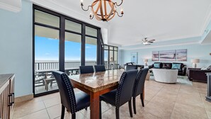 Uma sala de estar ampla com uma grande mesa de jantar, assentos confortáveis e vista para o oceano.