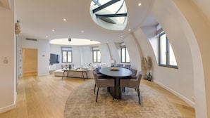A spacious living area with a round dining table, a large skylight, and a view of the city. - Chic penthouse Grand-Place  (Brussels)