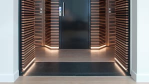 A modern elevator with a sleek black door and wooden paneling on the walls. - Chic penthouse Grand-Place  (Brussels)