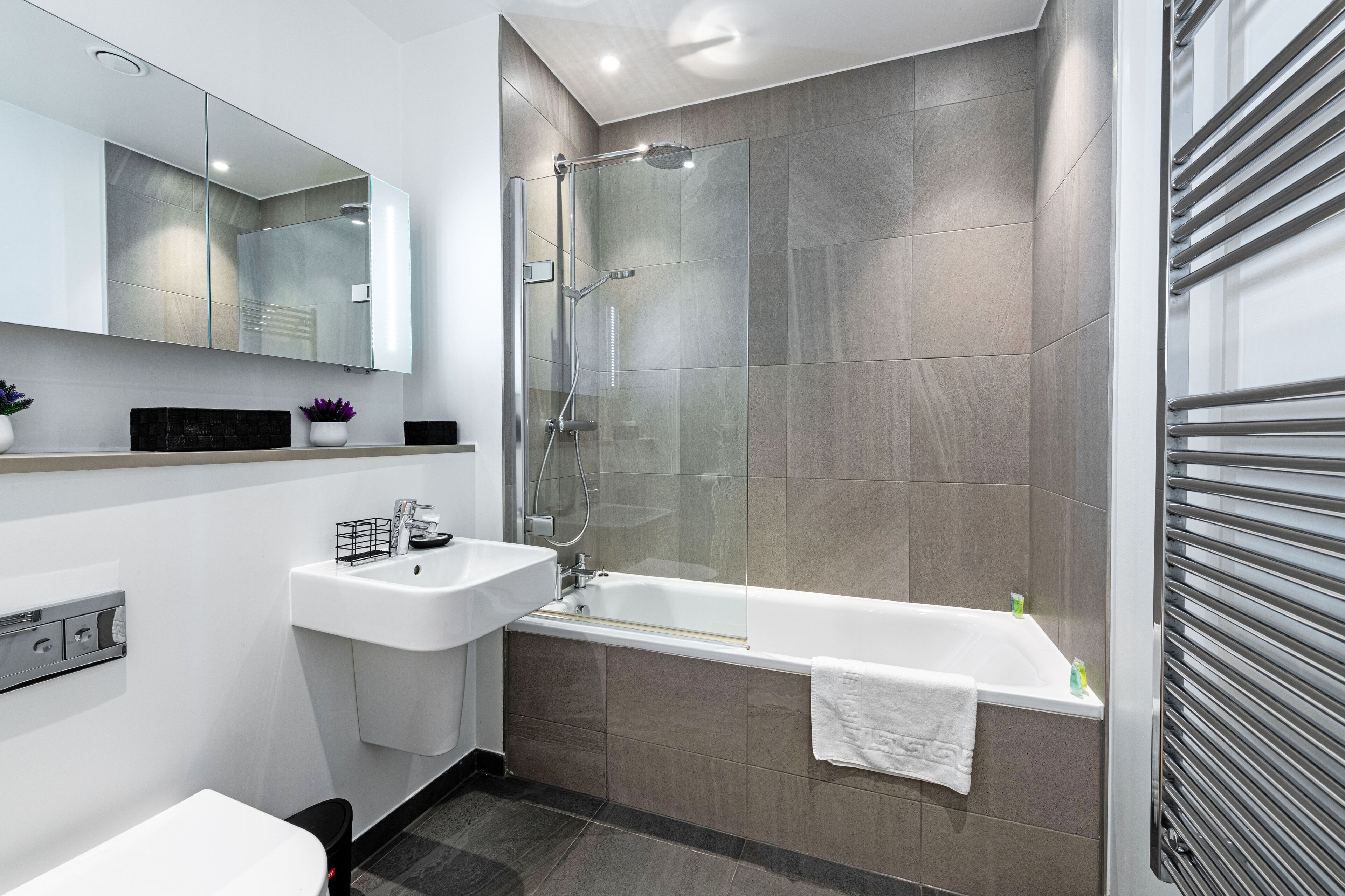 Une salle de bain moderne avec une douche à parois de verre, un lavabo blanc et une baignoire.