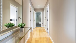 Un couloir avec une rambarde en verre, des plantes en pot et un miroir sur le côté gauche.