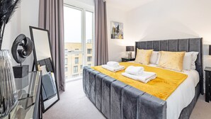 Une chambre d’hôtel moderne avec un grand lit, une table de chevet, un miroir et une vue sur la ville.