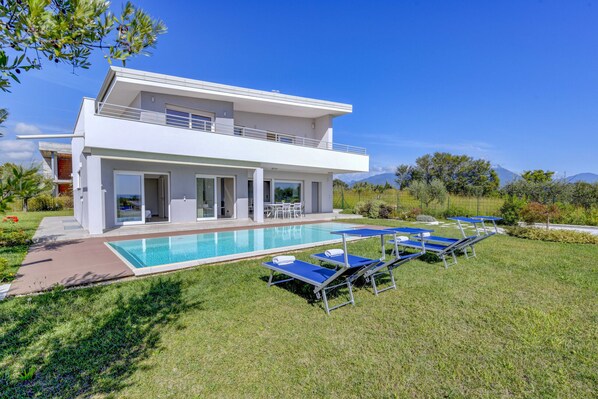 A modern two-story house with a swimming pool, outdoor seating, and a view of mountains. - Villa Easy chic in Moniga del Garda with private pool (Moniga del Garda)