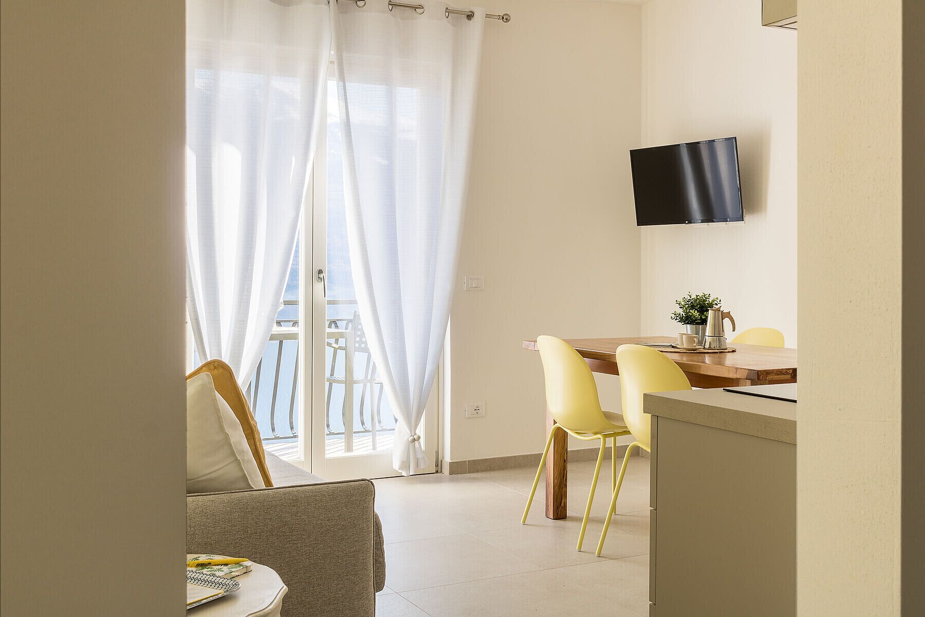 Une chambre moderne dotée d’un coin repas, d’un téléviseur fixé au mur et d’un balcon avec vue.
