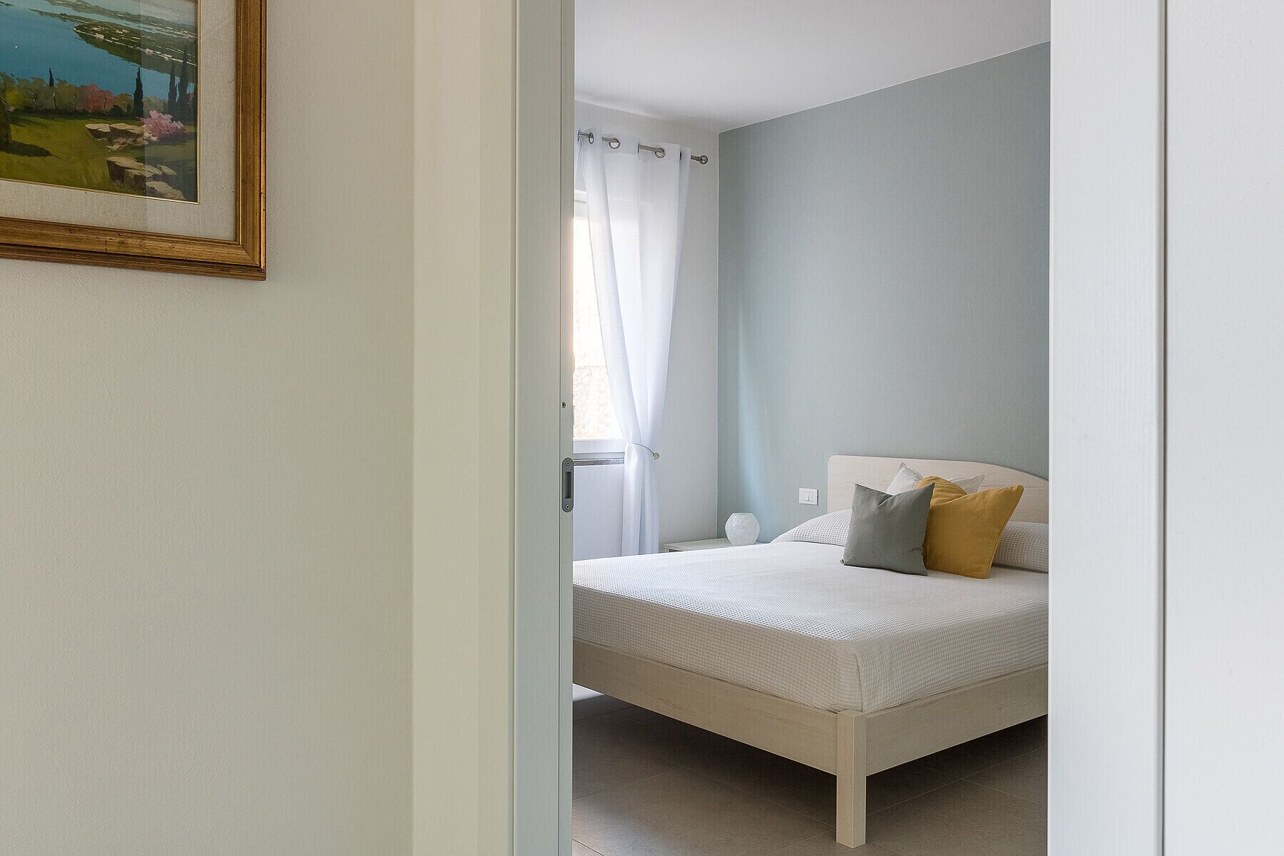 Une chambre à coucher avec un lit, une fenêtre avec des rideaux et un tableau accroché au mur.