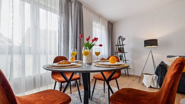 Comedor con mesa redonda, cuatro sillas y desayuno que incluye croissants y zumo de naranja.
