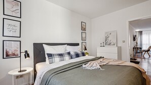 Un dormitorio moderno con cama, mesita de noche y una obra de arte colgada en la pared.