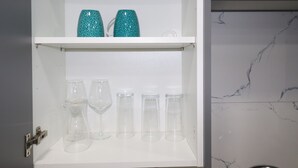 A white cabinet with shelves containing clear glassware and a white marble backsplash. - Impeccable 1-bed Apartment in Dartford (Dartford)