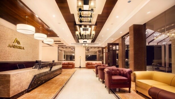 A hotel lobby with a reception desk, leather sofas, and a chandelier. - HOTEL AADRIKA (Chikkamagaluru)