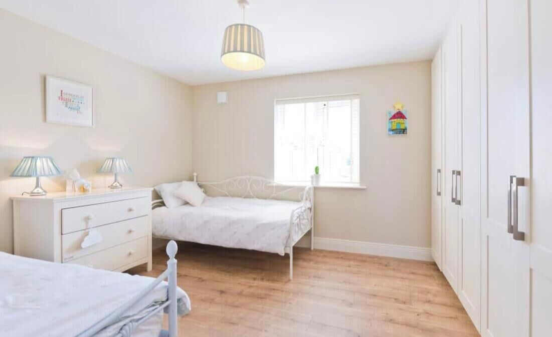 Um quarto com uma cama, mesas de cabeceira, uma janela e um guarda-roupa.