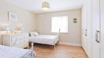 Um quarto com uma cama, mesas de cabeceira, uma janela e um guarda-roupa.