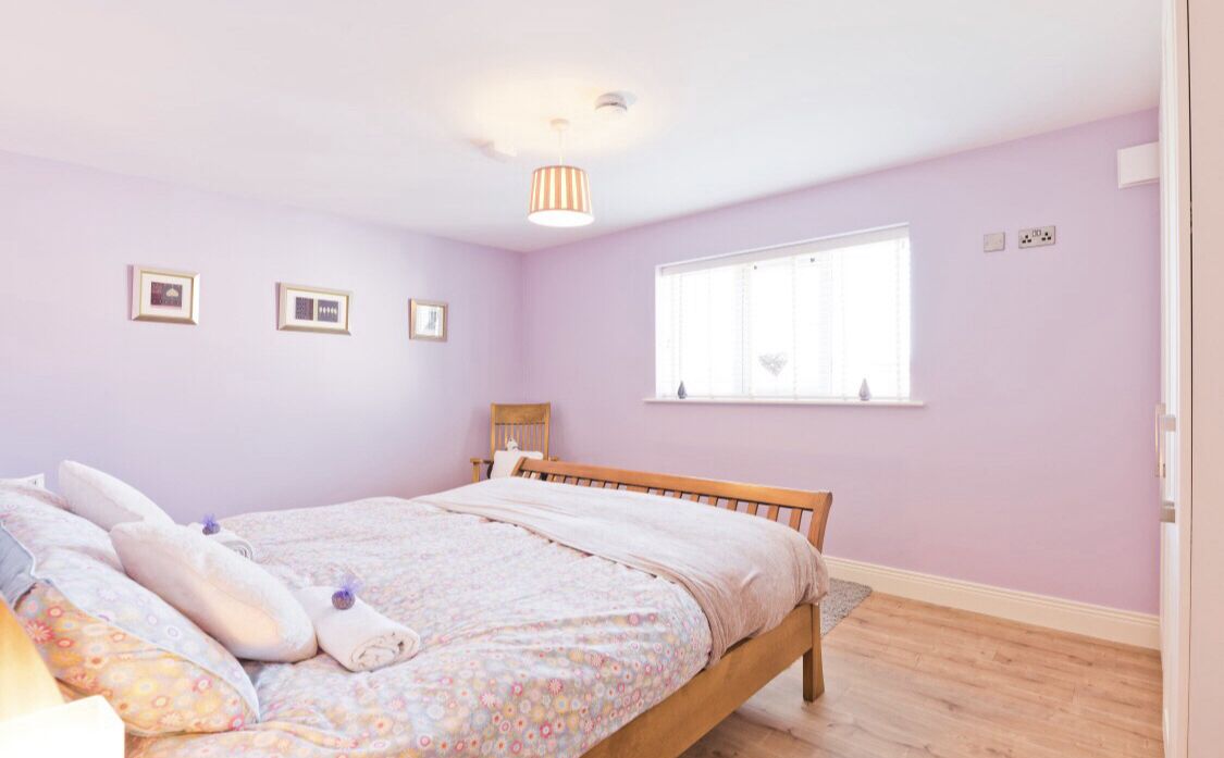 Un dormitorio con cama de madera, ventana con persianas y lámpara en el techo.