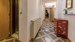 En hotellkorridor med ett element, en trädörr och ett rött skåp med blommönster.