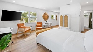 Et moderne hotelværelse med en stor seng, et skrivebord, et fjernsyn og et siddeområde med stole.