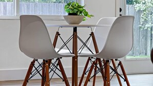 A dining area with two white chairs and a table, a potted plant on the table, and a window with a view of greenery. - Fresh & Bright Condo 1BR/1BA – Near Riverwalk (Fort Lauderdale)
