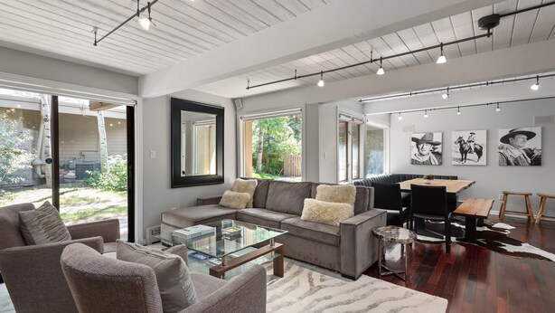 A modern living room with a sectional sofa, a glass coffee table, and a dining area with a wooden table and chairs. - Aspen Alps Apartment #107 2 Bedroom Condo by RedAwning (Aspen)