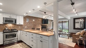 A modern kitchen with white cabinets, a large island, stainless steel appliances, and a brick accent wall. - Aspen Alps Apartment #107 2 Bedroom Condo by RedAwning (Aspen)