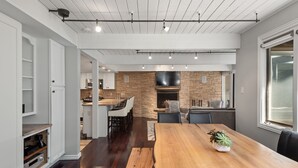 A modern kitchen with a brick wall, a large wooden dining table, and a built-in bar area. - Aspen Alps Apartment #107 2 Bedroom Condo by RedAwning (Aspen)